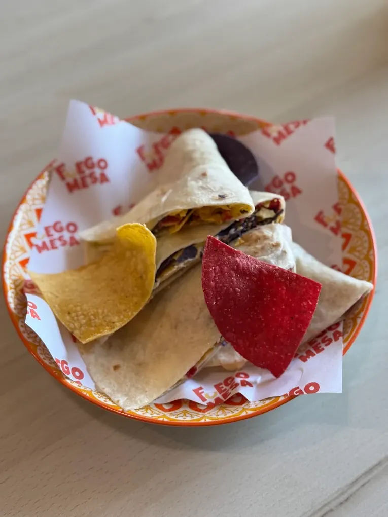 A flour tortilla wrap cut in half and served with corn tortilla chips on a Fuego Mesa plate