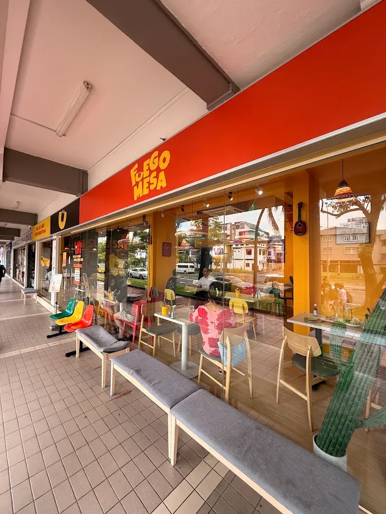 The Fuego Mesa shopfront on Race Course Road, with its red sign and coloured chairs at the window