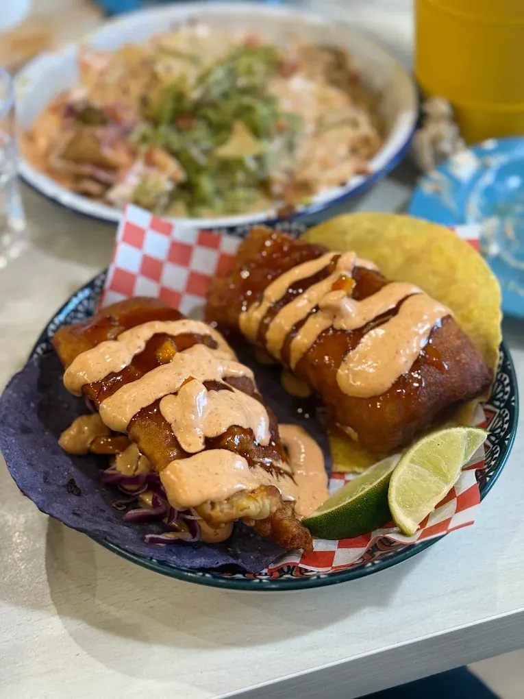Two beer-battered fish tacos on a blue corn tortilla with red cabbage and chipotle mayonnaise