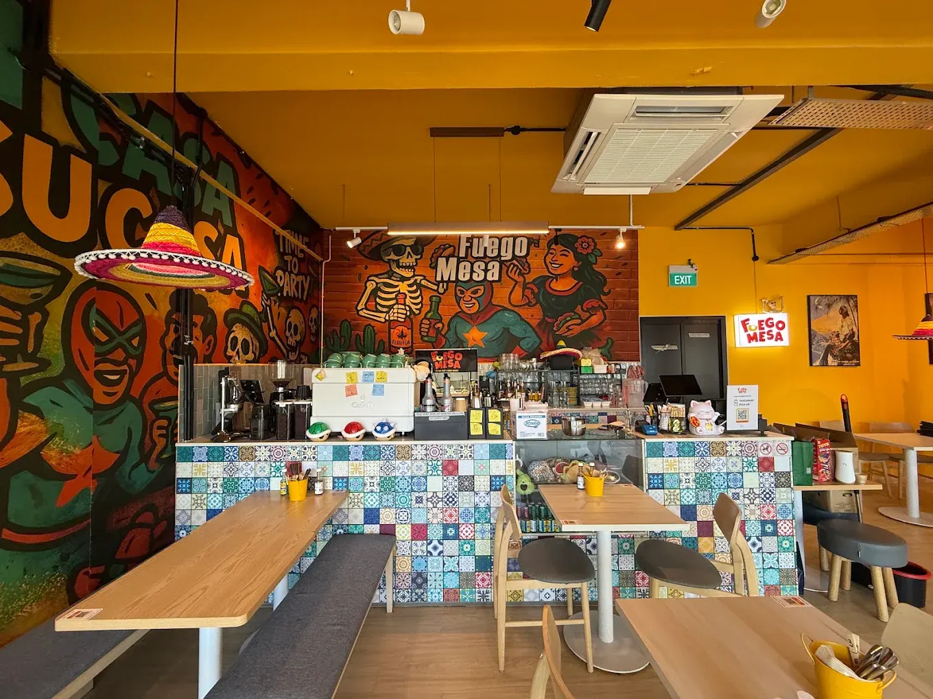 The Fuego Mesa counter with its mosaic-tiled front, skeleton and luchador mural and lit brand sign