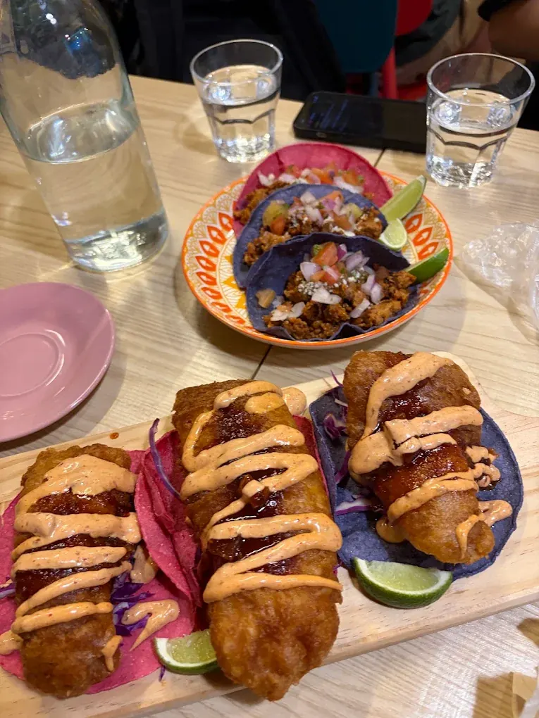 A table set with a board of fish tacos and a plate of blue corn tacos